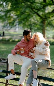 a man and woman sitting on a bench eating and smiling at each other | acupuncture for male fertility