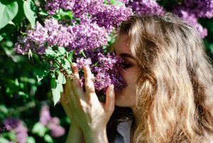a woman smelling purple lilacs