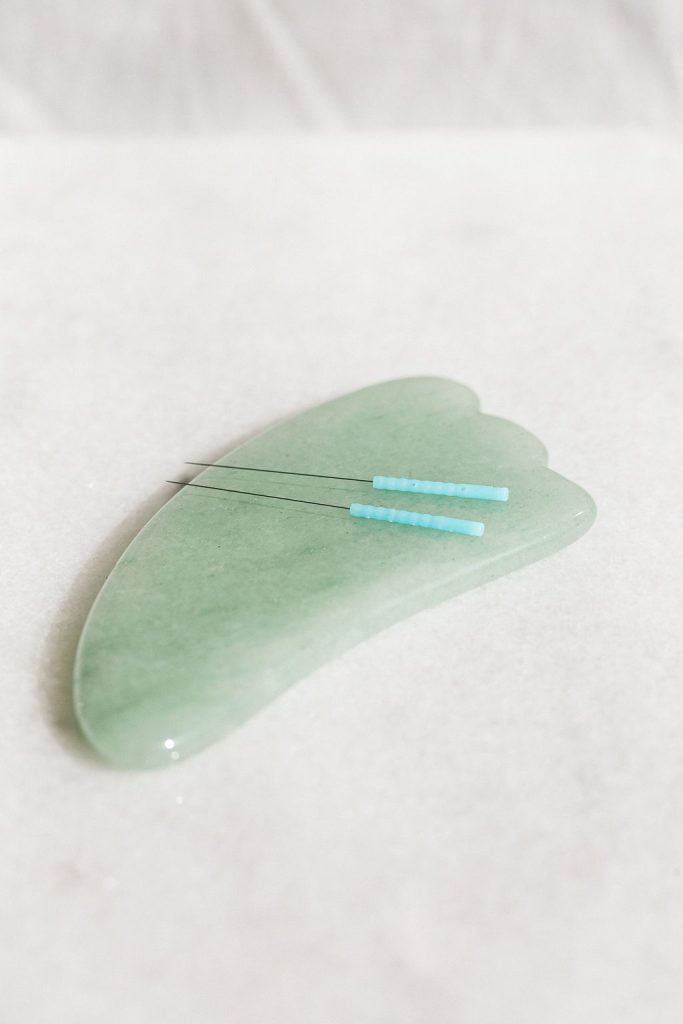 Cosmetic acupuncture before and after tools including facial needles and a jade gua sha stone.