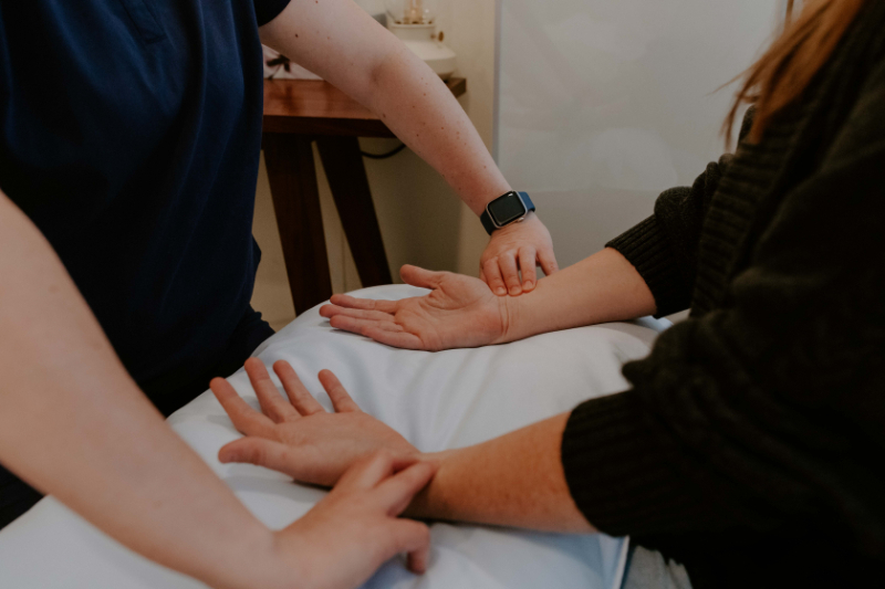 Acupuncturist checking pulse during adenomyosis and acupuncture consultation in a calm clinic setting.