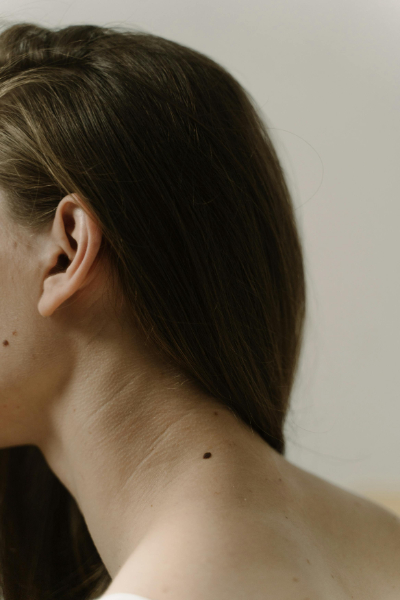 Close-up of a woman's ear and neck, showing placement area for ear seeding and auricular acupuncture.