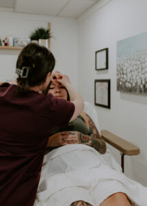 Acupuncturist placing needles on patient lying on table in calm, clean treatment room