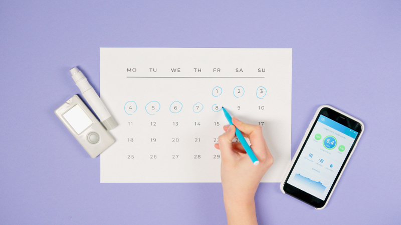 Calendar and hand marking dates during PCOS Awareness Month to track menstrual cycle changes.
